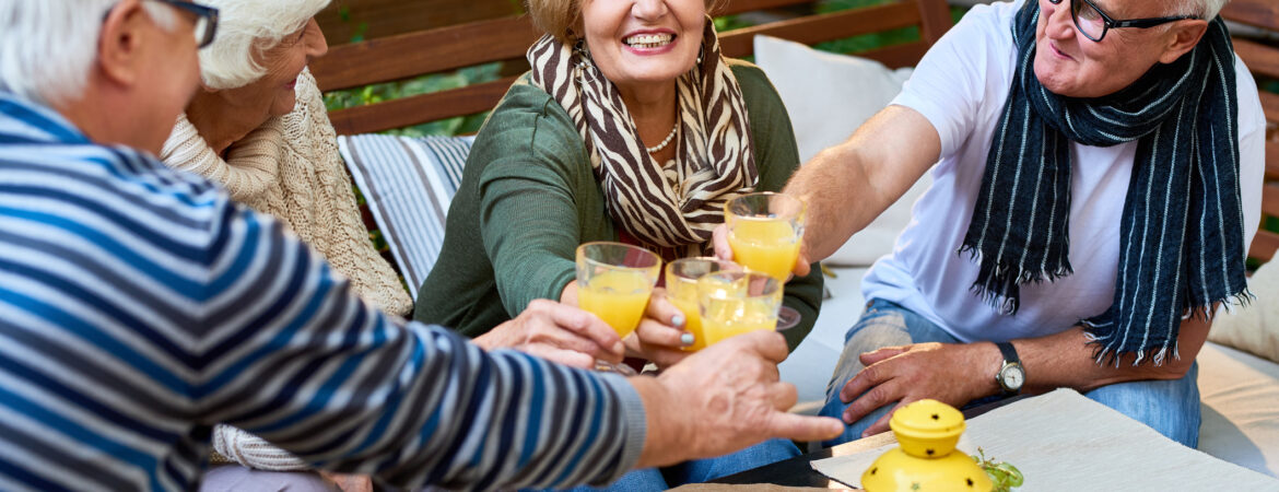 group of senior frieds toasting with glasses of orange juice during a Happy Hour.