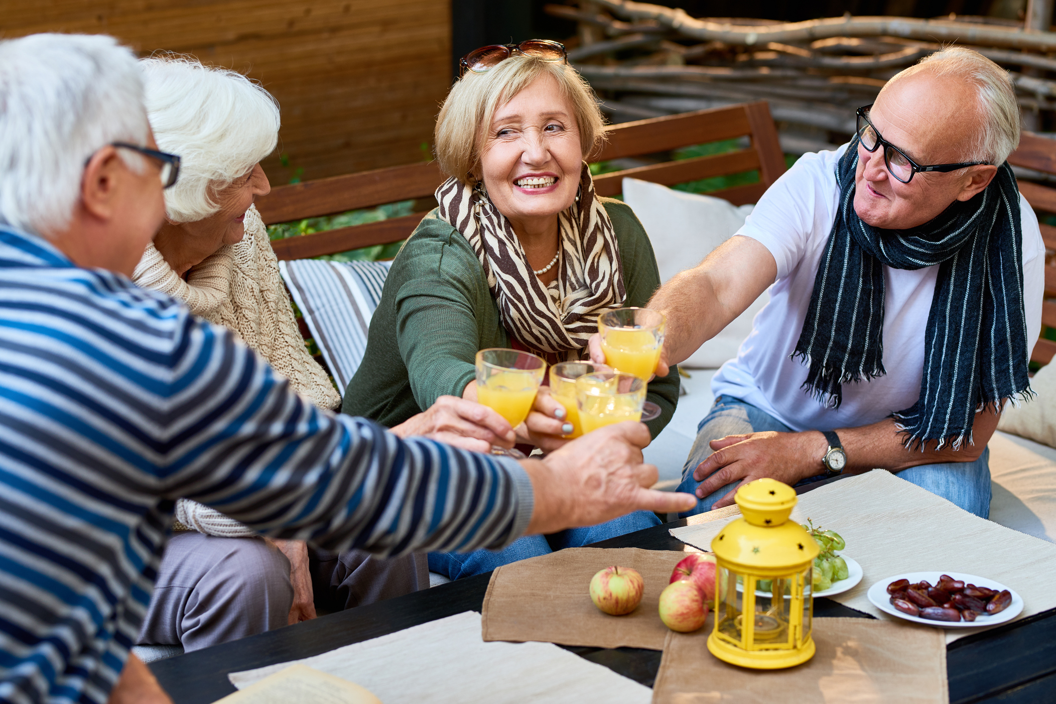 group of senior frieds toasting with glasses of orange juice during a Happy Hour.